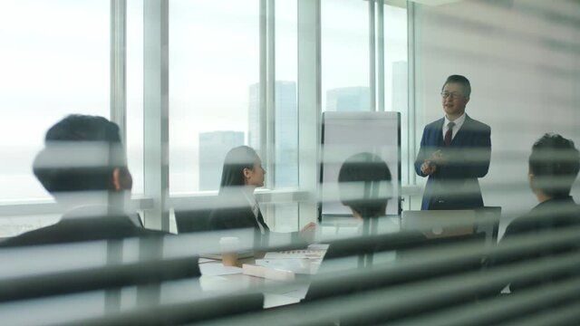 asian boss delivering a speech during team meeting in modern office