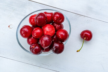 Obraz na płótnie Canvas ripe cherries in a glass bowl on a white wooden background