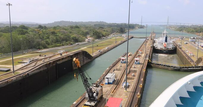 Panama Canal Gatun Locks Pacific Ocean POV. System lifts a ship 85 feet between the Atlantic and Pacific Ocean. Nation 52 miles long. Tug boats, electric train engines pull the cargo. Thousands ships.