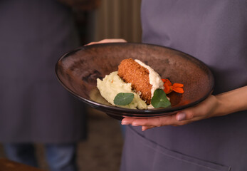 Young waitress with dish in restaurant, closeup