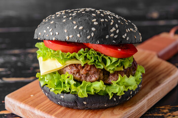 Tasty burger with black bun on table, closeup