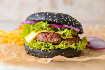 Tasty burger with black bun on table