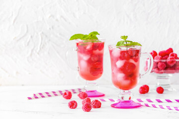 Cups of cold raspberry tea on white background