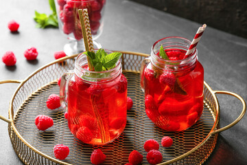 Mason jars of cold raspberry tea on dark background