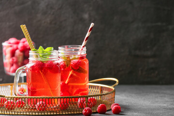 Mason jars of cold raspberry tea on dark background
