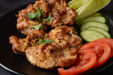 Grilled chicken steaks with tomatoes, herbs, olive oil, pepper,sliced cucumber and herbs.