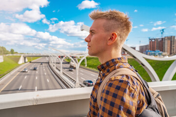 A young blond man in shirt looking at the road section of St. Petersburg Western high-speed diameter in the sunlight