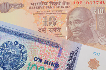A macro image of a orange ten rupee bill from India paired up with a blue, white and green ten thousand som note from Uzbekistan.  Shot close up in macro.