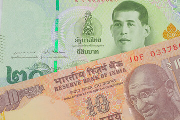 A macro image of a orange ten rupee bill from India paired up with a green twenty baht bank note from Thailand.  Shot close up in macro.