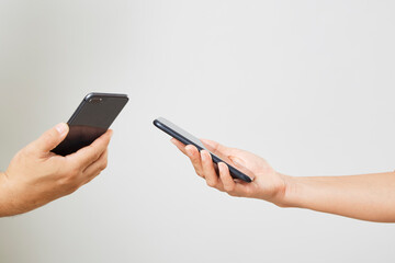 A male and female hands with phones opposite each other