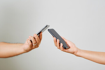 A male and female hands with phones opposite each other