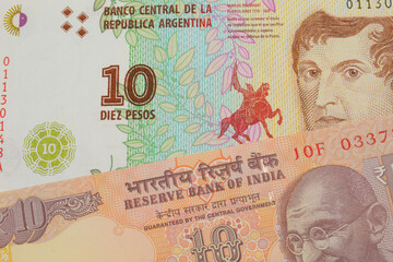 A macro image of a orange ten rupee bill from India paired up with a colorful ten peso note from Argentina.  Shot close up in macro.