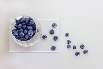 Blueberries in a glass on a white glass table., white wall background. Berries in a glass. Vegetarian and organic food concept. Top view.