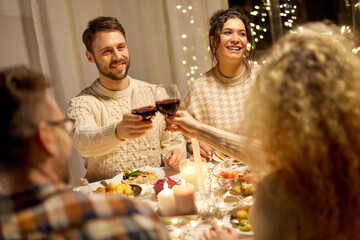 holidays, celebration and people concept - happy friends having christmas dinner at home drinking non-alcoholic red wine