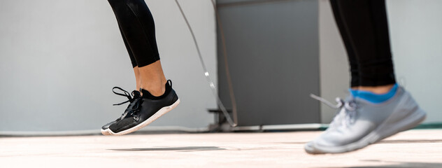 Legs of sports men doing jumping rope exercise outdoors on the floor, banner size