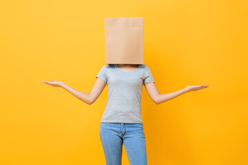 Anonymous woman in casual attire cover head with paper bag doing open hand gesture in yellow studio...