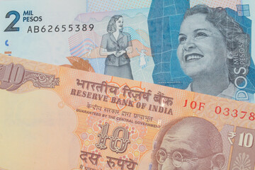 Fototapeta premium A macro image of a orange ten rupee bill from India paired up with a blue two thousand bank note from Colombia. Shot close up in macro.