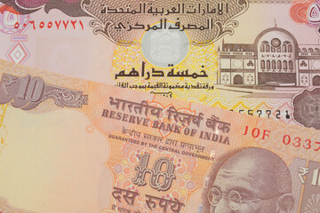 A macro image of a orange ten rupee bill from India paired up with a colorful five dinar bank note from the United Arab Emirates.  Shot close up in macro.