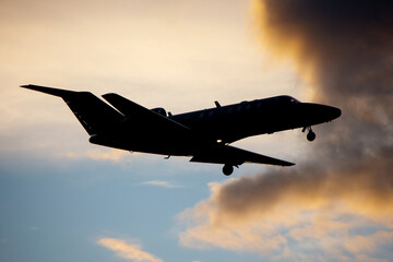 Silhouette of business jet landing on the background of sunset