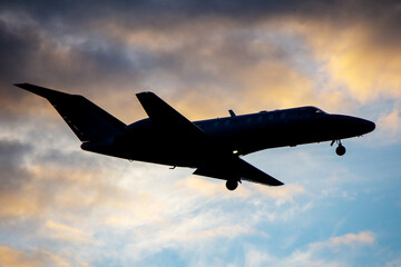 Fototapeta na wymiar Silhouette of business jet landing on the background of sunset