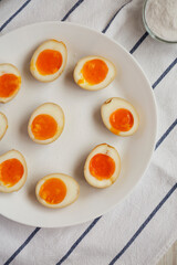 Homemade Unami Soy Sauce Eggs on a white plate, top view. Overhead, from above, flat lay.