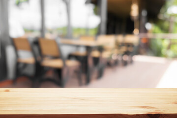Empty wooden desk space and blurry background of coffee shop or Restaurant for product display montage.