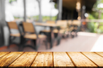 Empty wooden desk space and blurry background of coffee shop or Restaurant for product display montage.