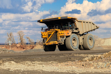 Huge yellow mining dump truck working in iron ore quarry. Mining industry