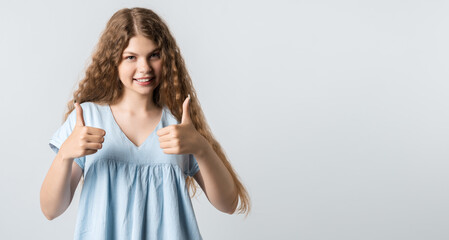 Attractive calm young woman with curly long hairstyle shows OKAY sign with both hands, demonstrates approval, isolated over white background. Copy space for your text