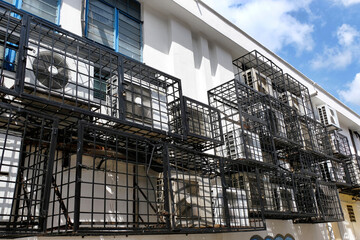 Fototapeta na wymiar AC condenser metal cages providing protection to air conditioner compressor outdoor split unit from loss and damage due to copper theft & vandalism, installed on the walls at the back of shop houses.