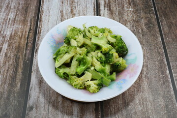 Traditional fried and stirred chopped fresh broccoli with soy sauce and pepper on the plate. Famous vegetarian food menu in Asia restaurant. 