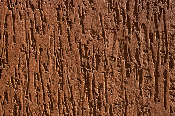 Decorative relief adhesive plaster. Brown stucco wall. The brown background of the wall.