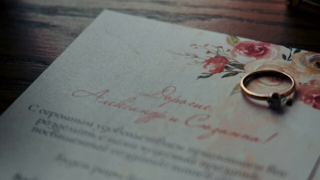  wedding ring lies on a cardboard invitation