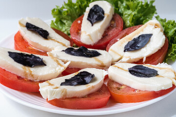 Caprese salad is a low-calorie cold Italian snack. The dish contains 3 ingredients: tomatoes, mozzarella and basil.