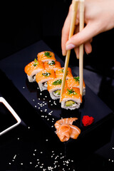 Sushi with salmon. Soy sauce, red caviar. Sushi on a black background.