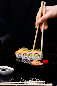 Sushi with salmon. Soy sauce, red caviar. Sushi on a black background.