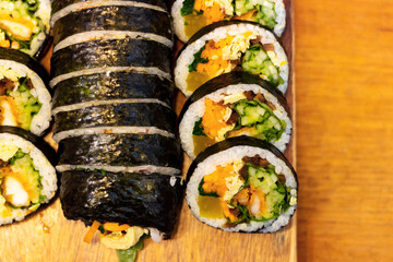 Korean kimpab rolls with vegetables and chicken on board, top view