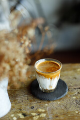 Glass of coffee with milk on rustic wooden table.
