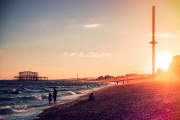 golden sunset on dusty beach with sea waves and pier in background