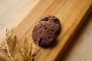 chocolate cookies and dark chocolate grain on wooden board background. for text concept advertising