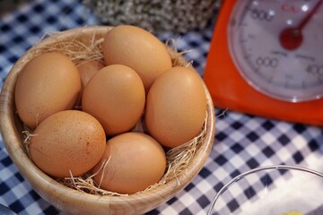 Group of eggs and baking ingredients with a dial scales in a kitchen.