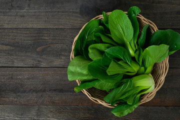 Fresh baby Bok choy in basket on wooden table.