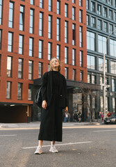 Full length portrait of a fashionable girl outdoors on the background of modern architecture,...