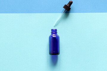 Blue glase bottle on background with two-colors background. Flat lay, cosmetic, oxigen, blue, fresh.