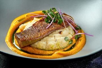 Baked beef tongue with mashed potatoes and carrots in a gray bowl on a black background. Close up. Selective focus