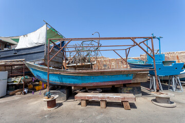 Old fishing boat in a dry dock, with blue sky in the background.
