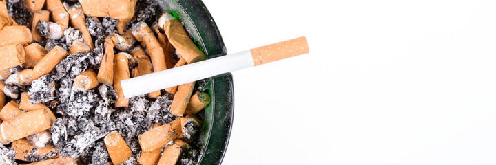 Many cigarette butts in the glass ashtray. Panoramic image