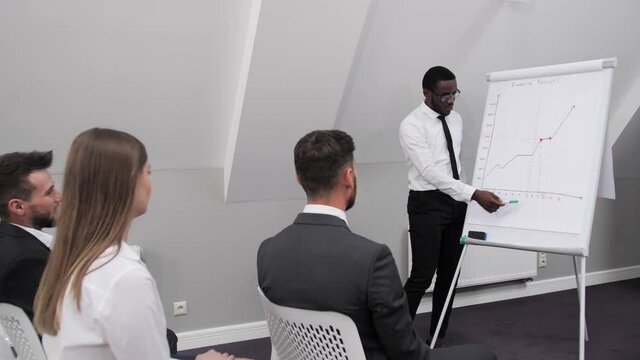 Afro american businessman makes a report in a conference room and analyzes the company's profits. The concept of teamwork.