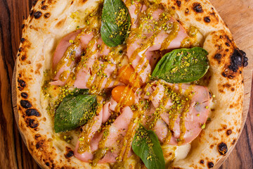 Pizza gourmet con mortadella, pomodori gialli, basilico, crema di pistacchio, granella di pistacchio e mozzarella