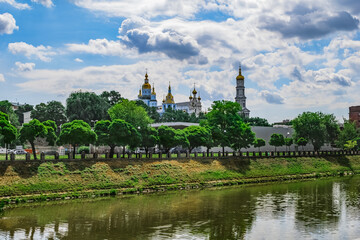 Kharkiv cityscape (Ukraine) with the Lopan river and the domes of the Dormition Cathedral and Pokrovsky Monastery. Kharkov panorama  with religious buildings on the background of green water and trees